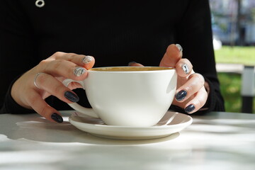Cup of coffee latte in the hands of a girl with a beautiful manicure