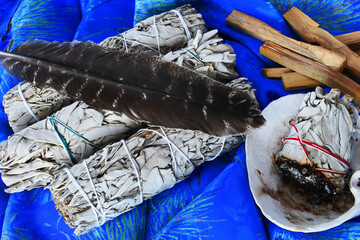 A top view image of ceremonial sage smudge sticks and sacred feather. 