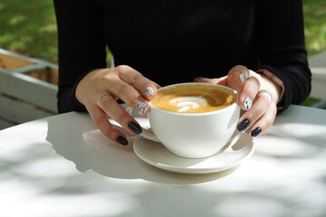 Cup of coffee latte in the hands of a girl with a beautiful manicure