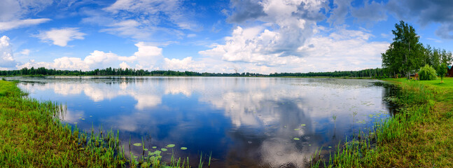 Stunning panorama with reflection of clouds in a forest lake