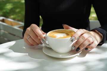 Cup of coffee latte in the hands of a girl with a beautiful manicure