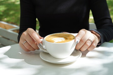 Cup of coffee latte in the hands of a girl with a beautiful manicure