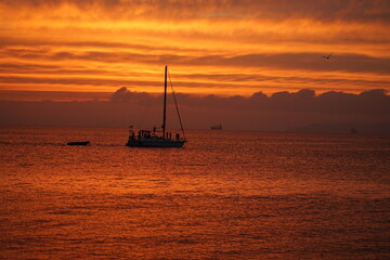Silhouette of a sea yacht against the background of a red sunset on the sea