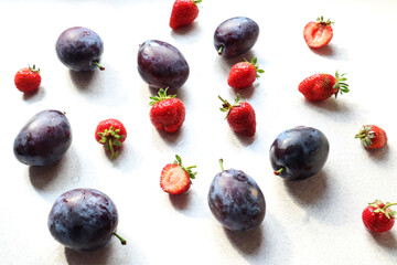 Background of ripe plums and strawberries, side view, close-up