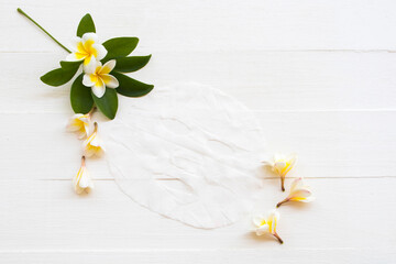 Obraz premium natural cosmetics herbal aroma sheet mask extract herbal flowers frangipani health care for skin face essence face mask arrangement flat lay style on background white