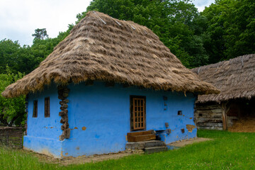Fototapeta na wymiar peasant house with thatched roof and tile built of clay and brick