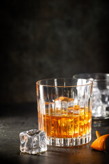 Glass of scotch whiskey with ice cubes on black background