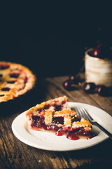 piece of Delicious homemade classic cherry pie with a flaky crust on dark rustic background