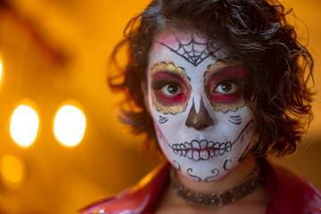 mujer joven latina mexicana maquillaje catrina calavera día de muertos chaqueta roja cabello corto luz cálida amarilla  fondo fuera de foco bokeh aislada close up