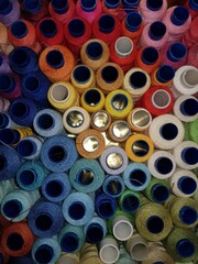 Multi-colored spools of thread lie in a box