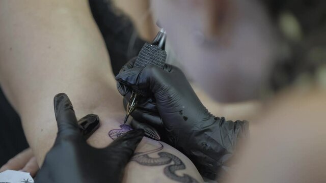 close-up. tattoo artist makes a snake tattoo on the wrist. tattoo parlor. tattoo master. 4k