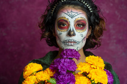 Mujer joven millennial bonita maquillaje catrina mexicana latina día de los muertos halloween cara pintada festividad disfraces punk moderna urbana modelo expresión flores colores cempasúchil seriedad