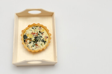 Quiche lorraine en bandeja de madera sobre fondo blanco. Aislado, recortable.