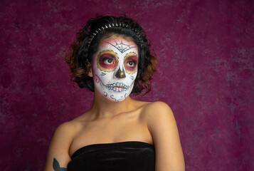Mujer joven millennial bonita maquillaje catrina mexicana latina día de los muertos halloween calavera cara pintada festividad disfraces fondo rosa punk moderna urbana modelo expresión mirada elegante