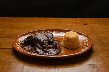 Mole, comida tipica mexicana. Servida en plato de barro sobre mesa de madera.