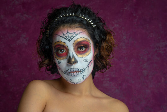 Mujer joven millennial bonita maquillaje catrina mexicana latina día de los muertos halloween calavera cara pintada festividad disfraces fondo rosa punk moderna urbana modelo expresión mirada elegante
