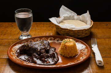 Mole, comida tipica mexicana. Servida en plato de barro sobre mesa de madera.