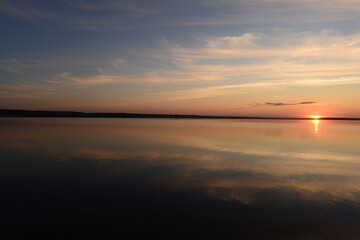 Fototapeta na wymiar Sunbeam at sunset on the blue calm water of the lake