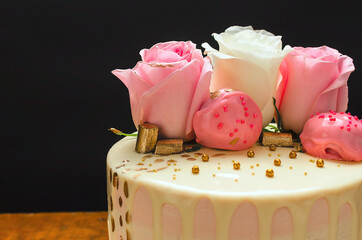 Hermoso pastel decorado con rosas naturales y chocolates, sobre mesa de madera. Hecho en casa.