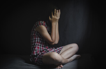 Lonely scared young girl sitting in dark room, Children abuse