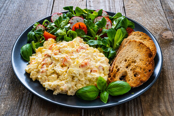 Vegetable mayonnaise salad with toasts on wooden table
