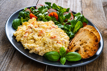 Vegetable mayonnaise salad with toasts on wooden table
