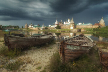 Two wooden boats on the shore and a monastery on the background