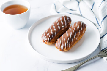Fresh eclairs on a plate with chocolate glaze