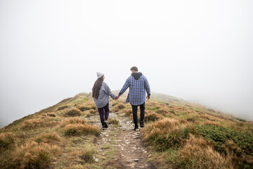 Fototapeta na wymiar young couple traveling in the mountains, the road is in fog