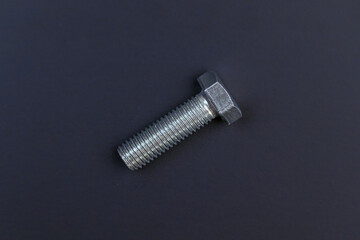 Fixing material. Construction supplies. Metal bolts and nuts on a dark background