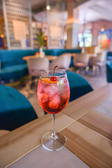 A glass with the red citrus cocktail. Alcohol summer beverage in a wine glass. Refreshing drink with ice.