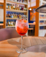 A glass with the red citrus cocktail. Alcohol summer beverage in a wine glass. Refreshing drink with ice.