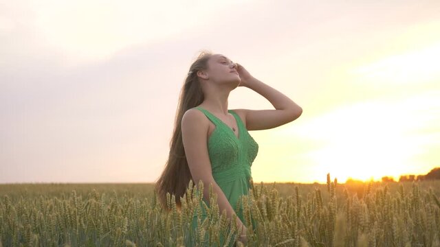 A young girl in the park throws her hair up. Girl model demonstrates beautiful long healthy hair. Hair develops in the wind.