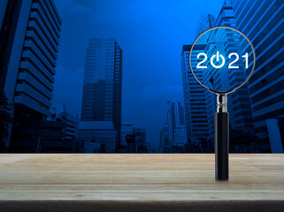 2021 start up flat icon with magnifying glass on wooden table over modern office city tower and skyscraper, Business happy new year 2021 concept