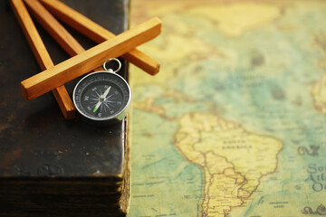 Travel and adventure search concept. Vintage aged map with a shabby book and compass. Shabby book and compass on the table.