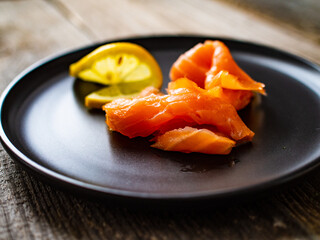 Smoked salmon with lemon served on black plate