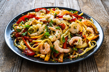 Spaghetti with prawns and vegetables on wooden background
