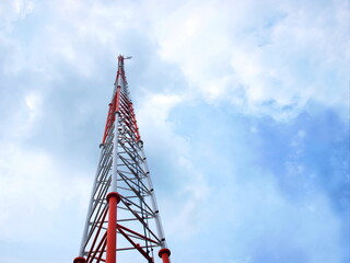 Structure of radio communication towers. Red and white telecommunication tower on white cloud sky background. Selective focus