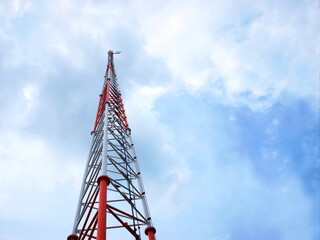 Structure of radio communication towers. Red and white telecommunication tower on white cloud sky...