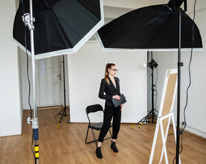 Photo shoot backstage. Professional photography. Female producer standing in modern studio with light equipment white backdrop. Master class. Creative crew.