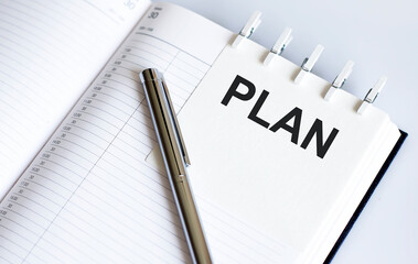 text PLAN on the short note texture background with pen