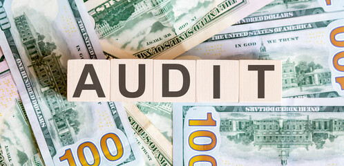 Concept words AUDIT on wooden blocks on a beautiful background from dollar bills.