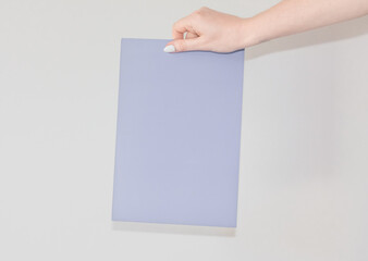  Blank colored sheet of cardboard in a womans hand on a white background with text space. A sheet for announcing and informing people. Information plate