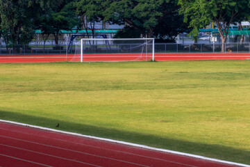 Fototapeta premium Red running track in sports fields and green grass