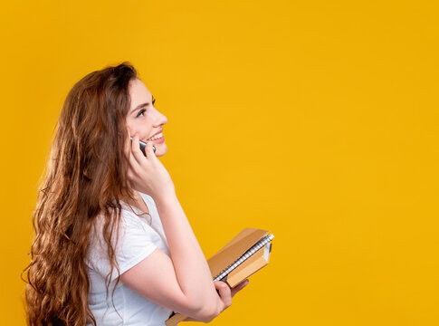 Phone call. Course promotion. Profile portrait of happy brunette woman with long hair asking for details looking at copy space for contact information isolated on orange. Commercial background.
