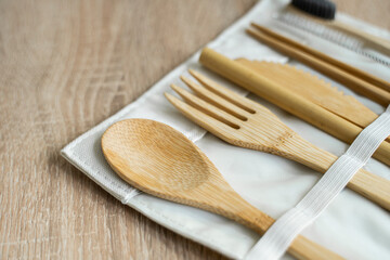 Eco friendly bamboo cutlery set in a case on a table. Zero waste concept. Set of bamboo cutlery in a case on a laying on a table. Spoon, fork, knife, toothbrush, tube and chinese sticks.