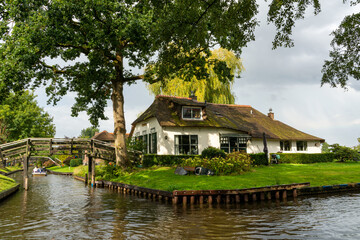 Fototapeta na wymiar Traditional thatched roof house at the canal in Giethoorn
