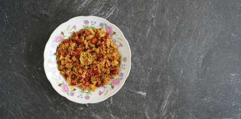 Salted shredded fish or abon is a traditional Indonesian food made from mashed salted fish, it tastes salty, spicy and delicious. Served on a white plate and stone pad.