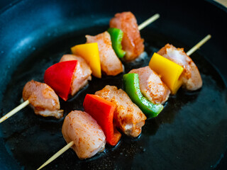 Uncooked skewers in frying pan 