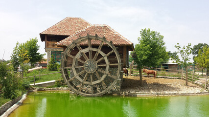 Obraz premium Old mill with a large wooden wheel in a landscaped tourist environment